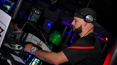Boston-area DJ Artie V spinning music on soundboard in a dark nightclub.