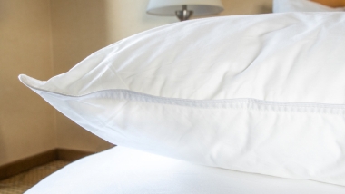 White Memoryfil pillow on white bed in hotel room.