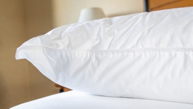 Firm Gel Fiber pillow in white on white bed in hotel room.