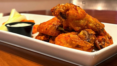 Bone-in buffalo wings with ranch, celery, and carrots on a white plate in Hops House 99 restaurant.