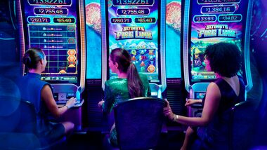 Group of female friends playing slot machines next to each other in a casino.