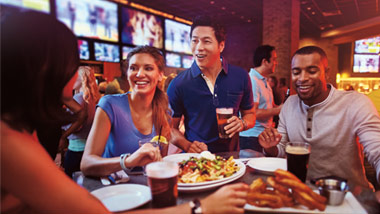 friends sharing nachos, wings and beer at a sports bar